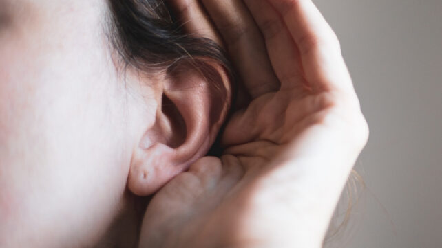 person with hand next to ear