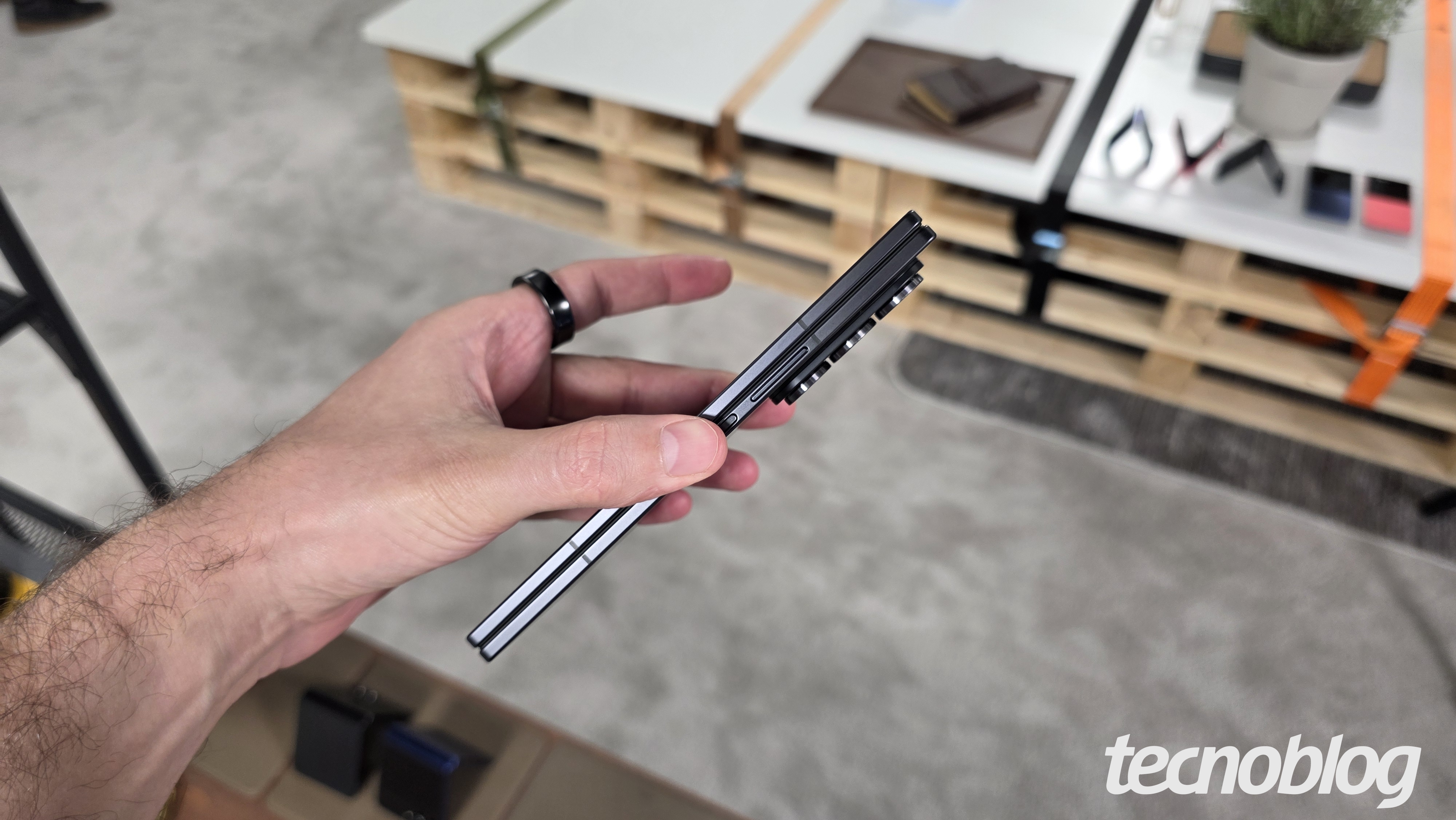Mão segurando smartphone dobrável fechado, visto pela lateral