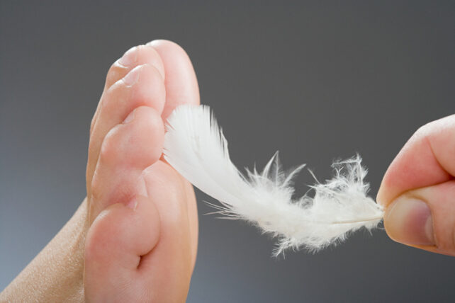 Hand tickling foot with feather