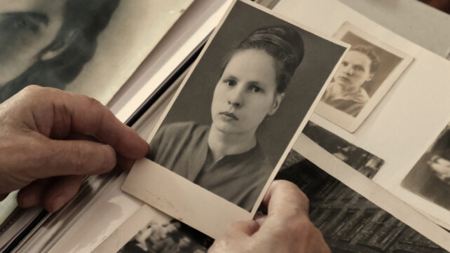 old black and white photograph of a woman's face held in an aging person's hands