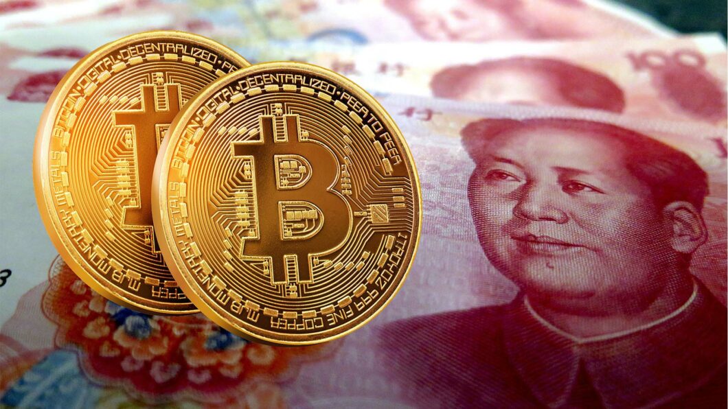 Ilustração mostra duas moedas ilustrando o bitcoin, ao lado de notas de yuan chinês