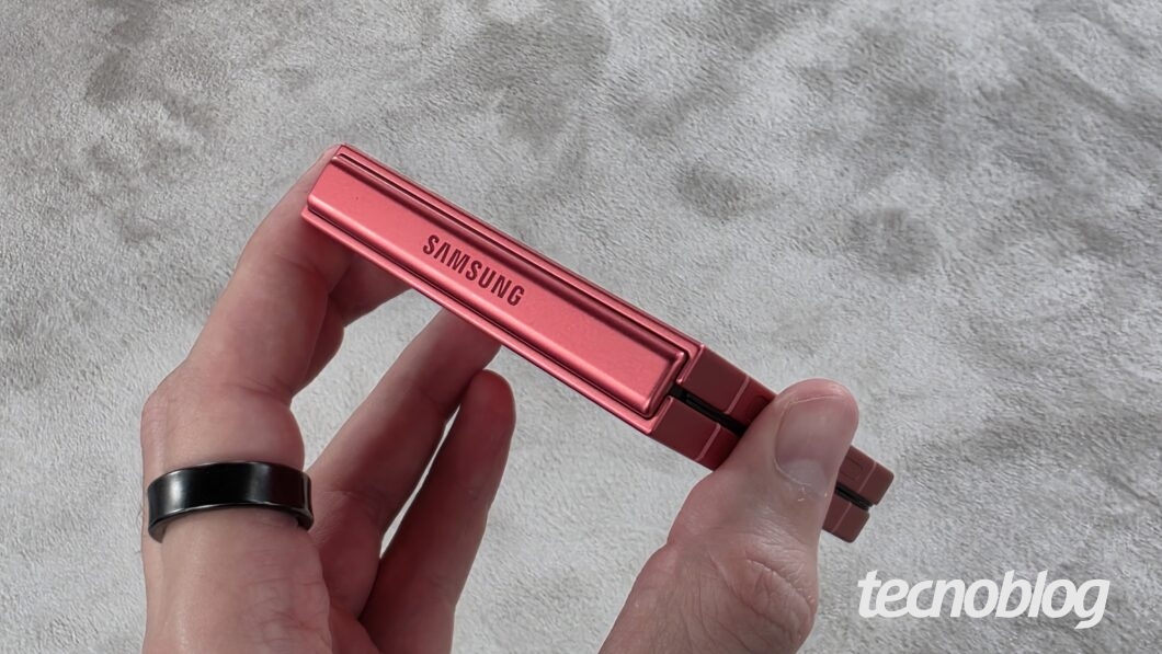 Mão segurando smartphone dobrável flip exibindo a dobradiça