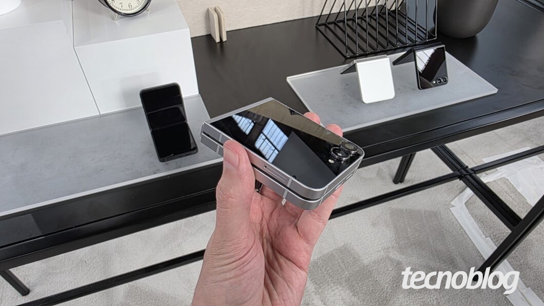 Mão segurando smartphone dobrável fechado, mostrando o design