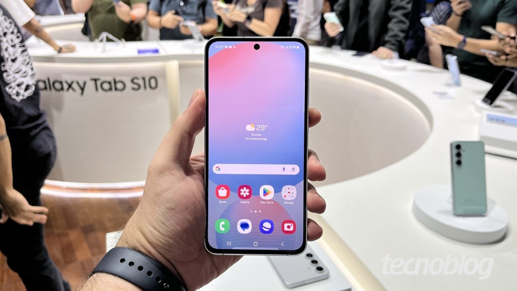 Mão esquerda segurando Galaxy S24 FE, com a tela voltada para frente
