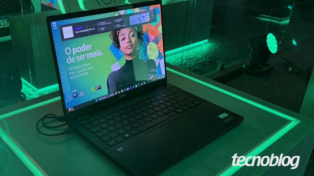 Notebook preto com imagem verde na tela, sobre bancada de pedra