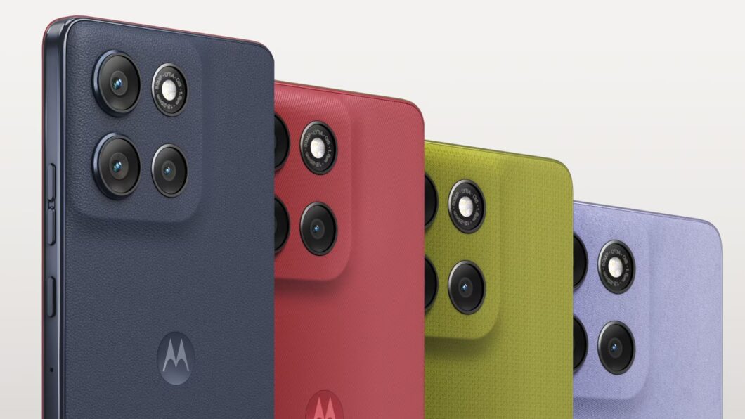Imagem mostra quatro smartphones Moto G86 da Motorola, vistos de perto em um ângulo lateral-superior, com as partes traseiras voltadas para a câmera. Da esquerda para a direita, os aparelhos são: azul-marinho, vermelho, verde-limão e lilás. Todos exibem um módulo de câmera retangular proeminente com duas lentes grandes e um flash. O logo estilizado da Motorola, um "M", é visível na parte inferior de cada aparelho.