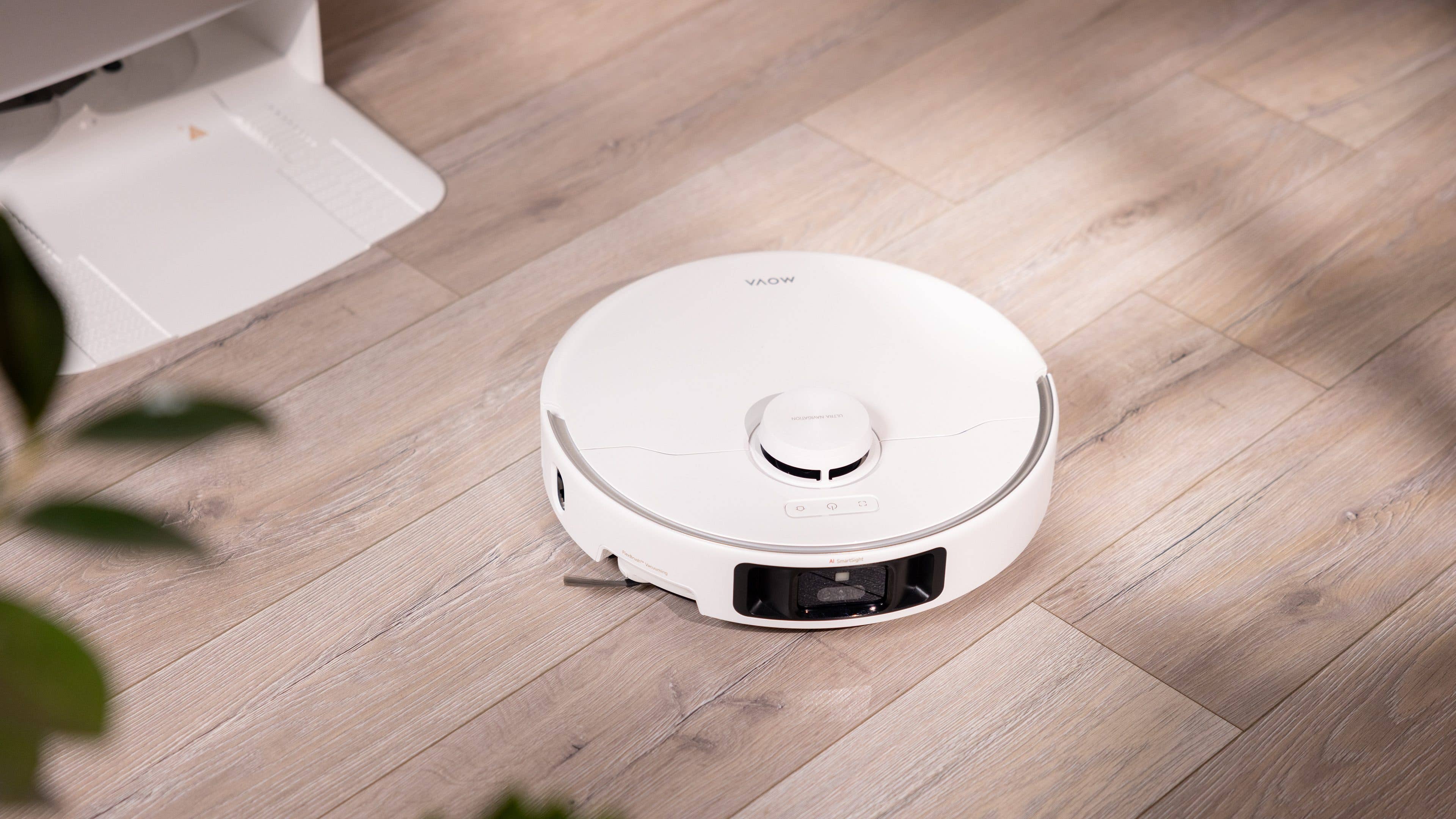 Ein weißer, roboterartiger Staubsauger auf einem Holzboden.