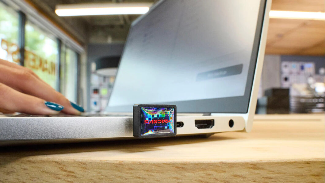 SanDisk Extreme Fit de 1 TB conectado a um notebook em ambiente de trabalho. O design compacto permite uso contínuo sem interferir no fechamento da tampa, reforçando a proposta de armazenamento 'plugue e esqueça