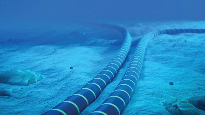 Imagem subaquática digital que mostra dois cabos de fibra óptica submarinos grossos e pretos, dispostos paralelamente no fundo do oceano