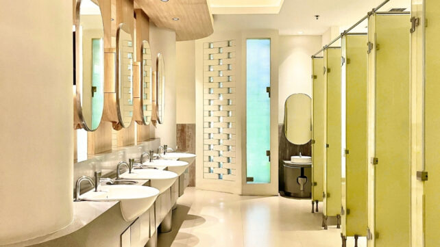 A row of public toilet cubicles with mirrors and basins facing them