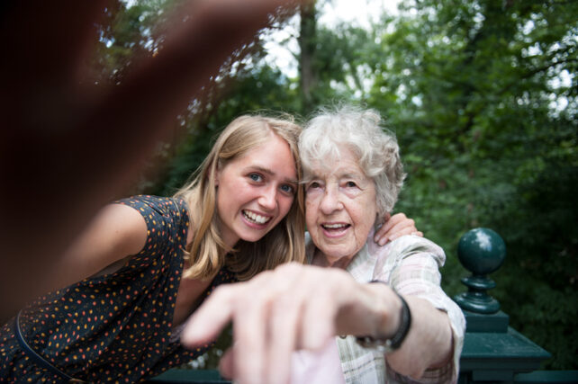 An older and younger woman posing together for a phone selfie