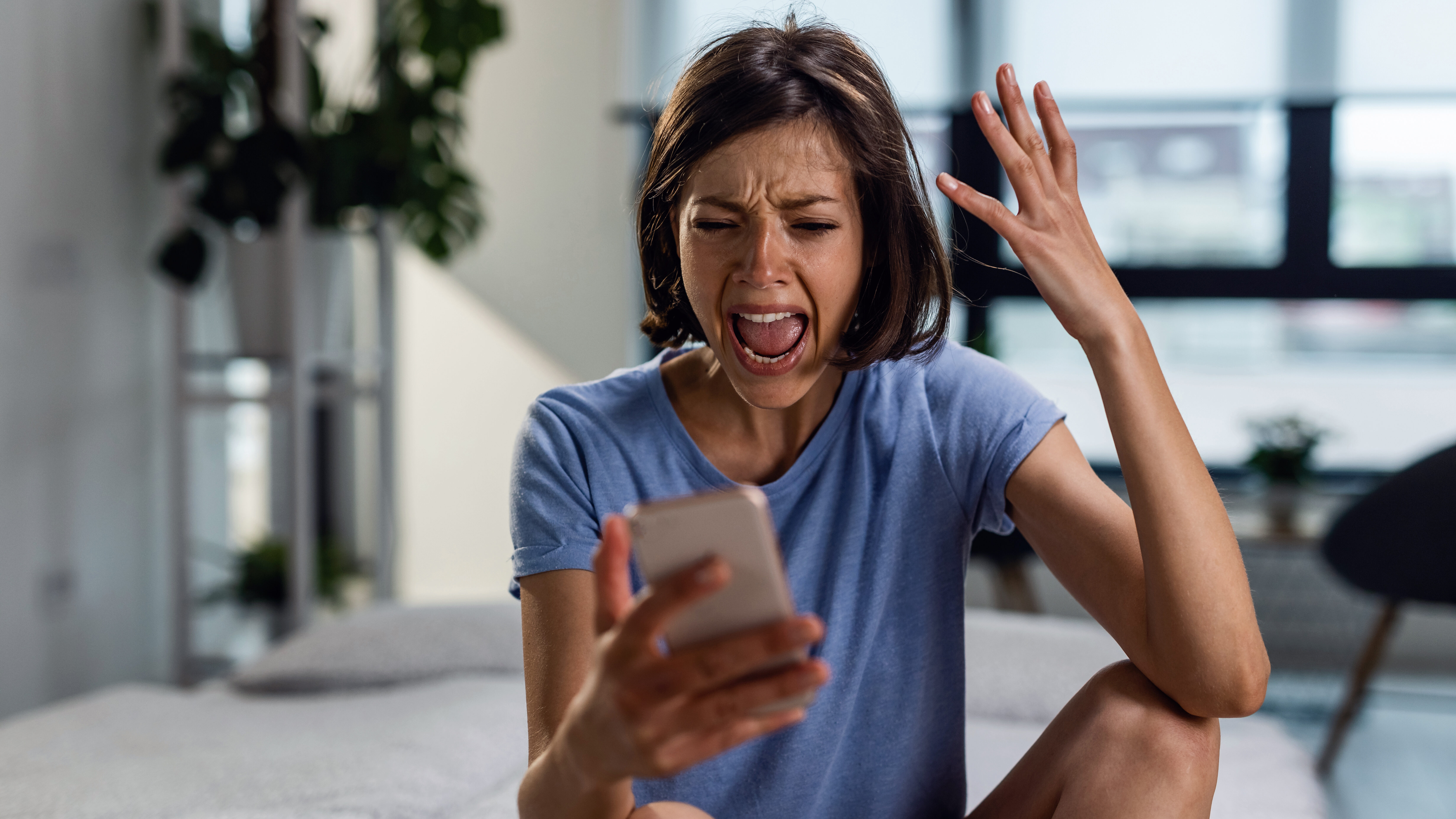 Imagem mostra uma mulher gritando para um smartphone, demonstrando raiva