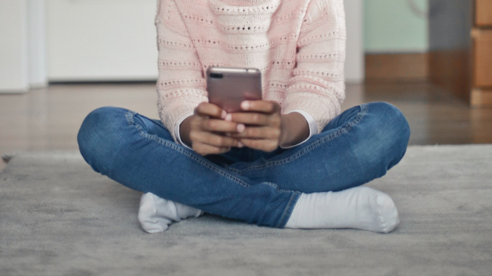 Imagem mostra uma criança com um celular nas mãos