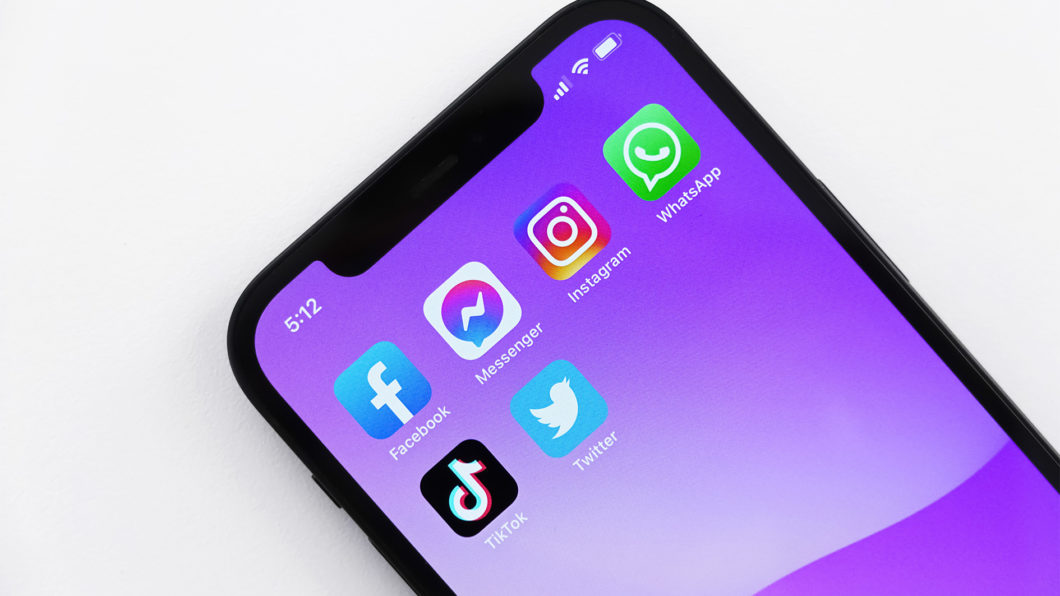 Imagem mostra um iPhone com aplicativos de redes sociais na página inicial