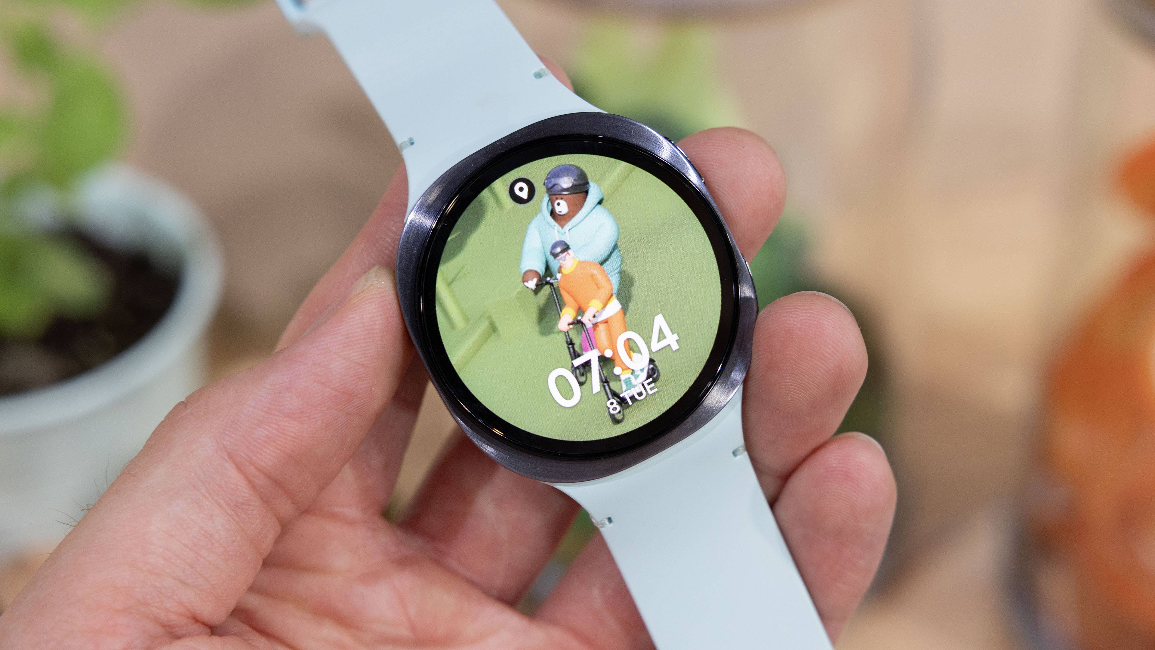 A person holding a Samsung Galaxy Watch 8 displaying a colorful cartoon character interface.