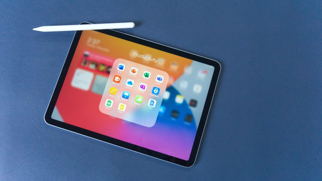 um tablet com uma caneta stylus em uma mesa azul exibindo uma janela com aplicativos de produtividade
