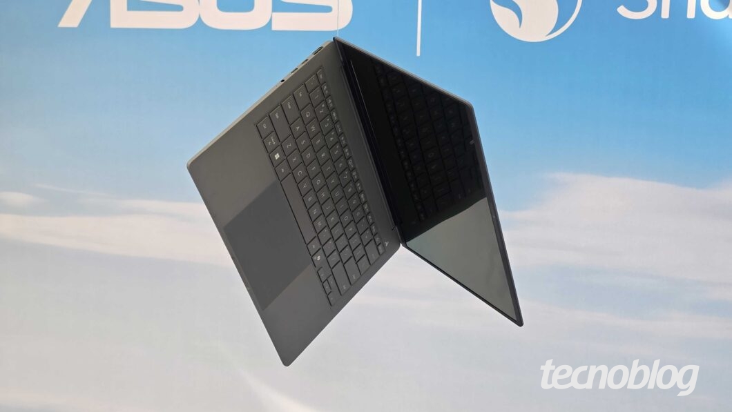 Fotografia mostra um notebook Asus Book A14 preto suspenso durante uma exposição.