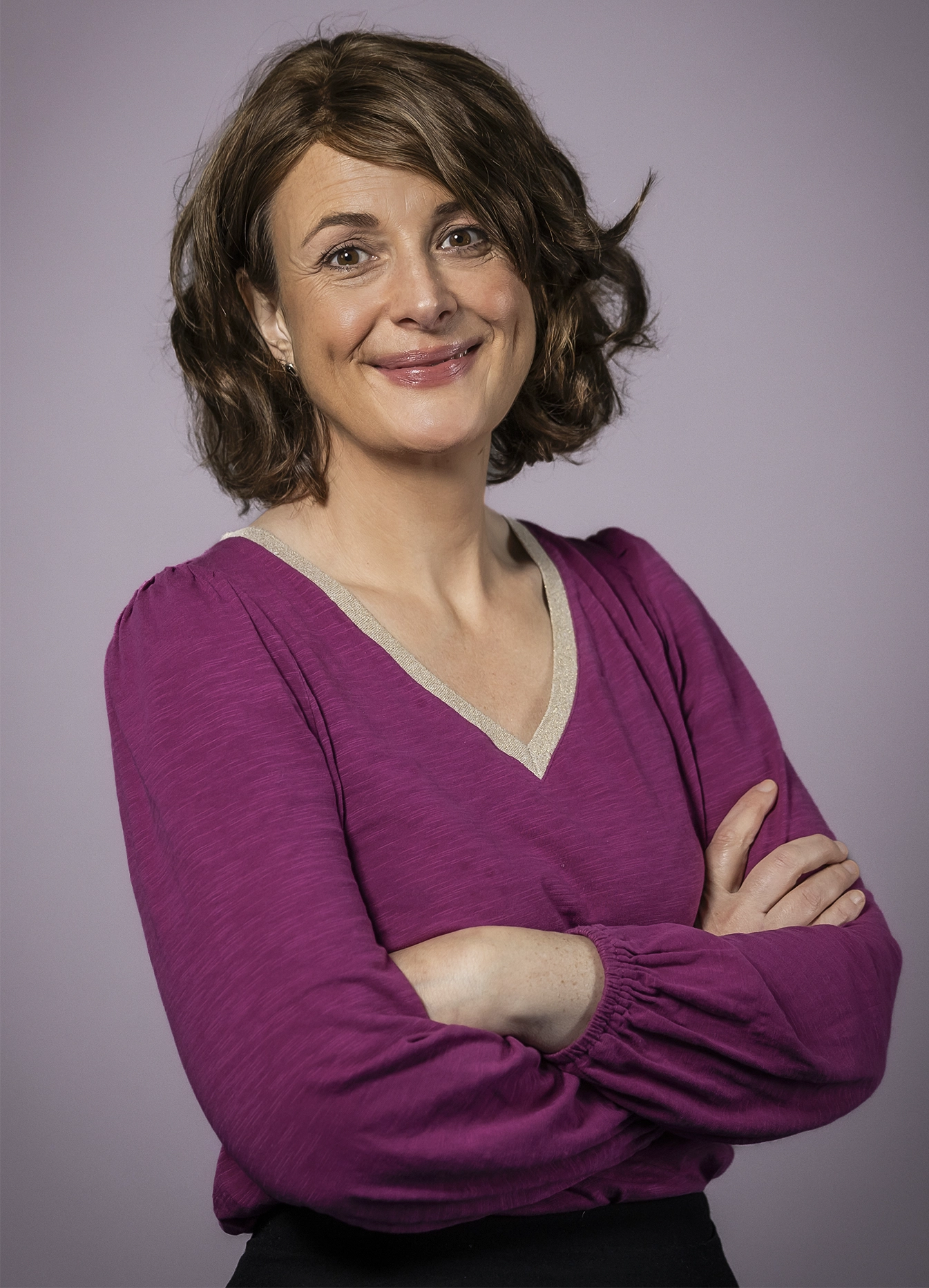 A smiling woman with her arms crossed