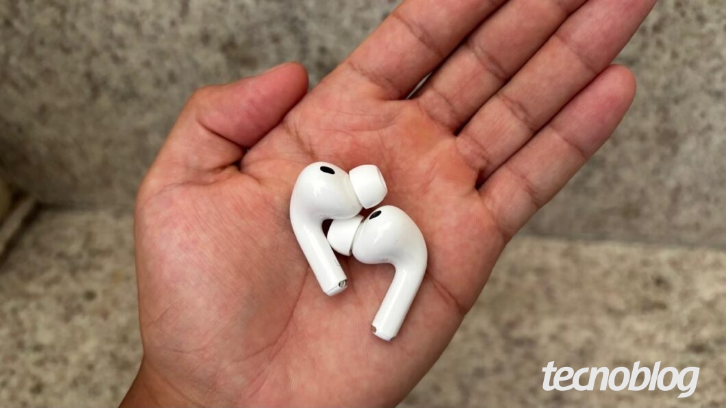 Uma mão segurando os dois fones AirPods Pro 3 fora do estojo