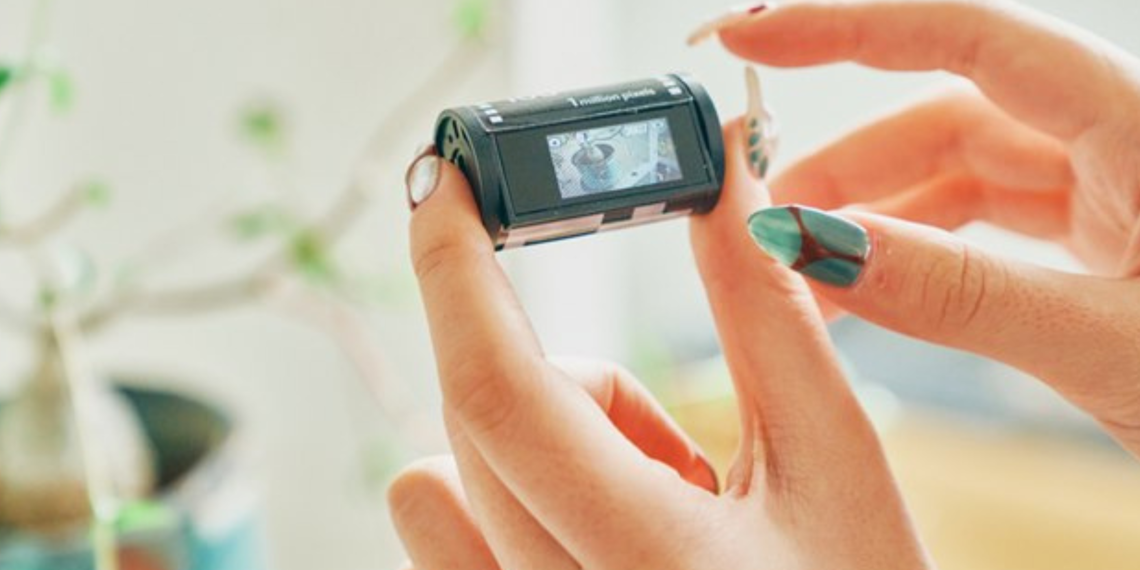 Imagem mostra uma câmera OPT100 Neo Film sendo segurada na mão