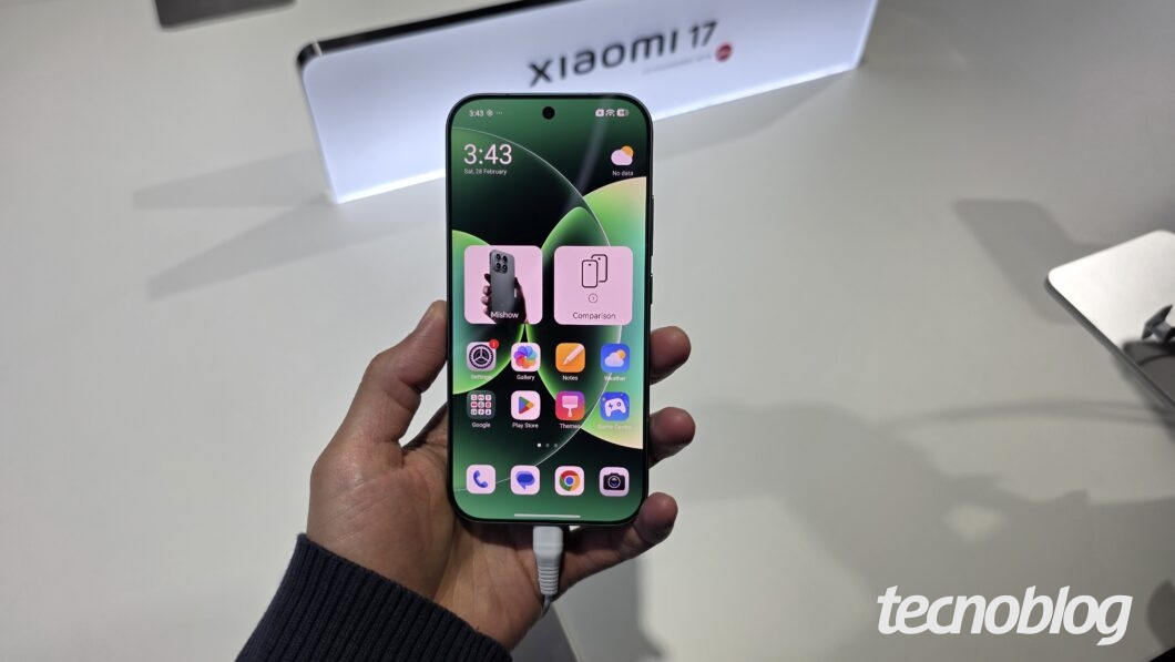 Mão segurando Xiaomi 17 com tela acesa, exibindo ícones de aplicativos na interface HarmonyOS 3