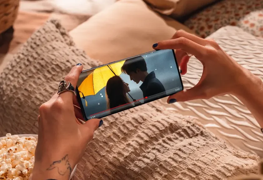 Pessoa segurando um smartphone Motorola Edge 60 Fusion enquanto assiste a um filme romântico.