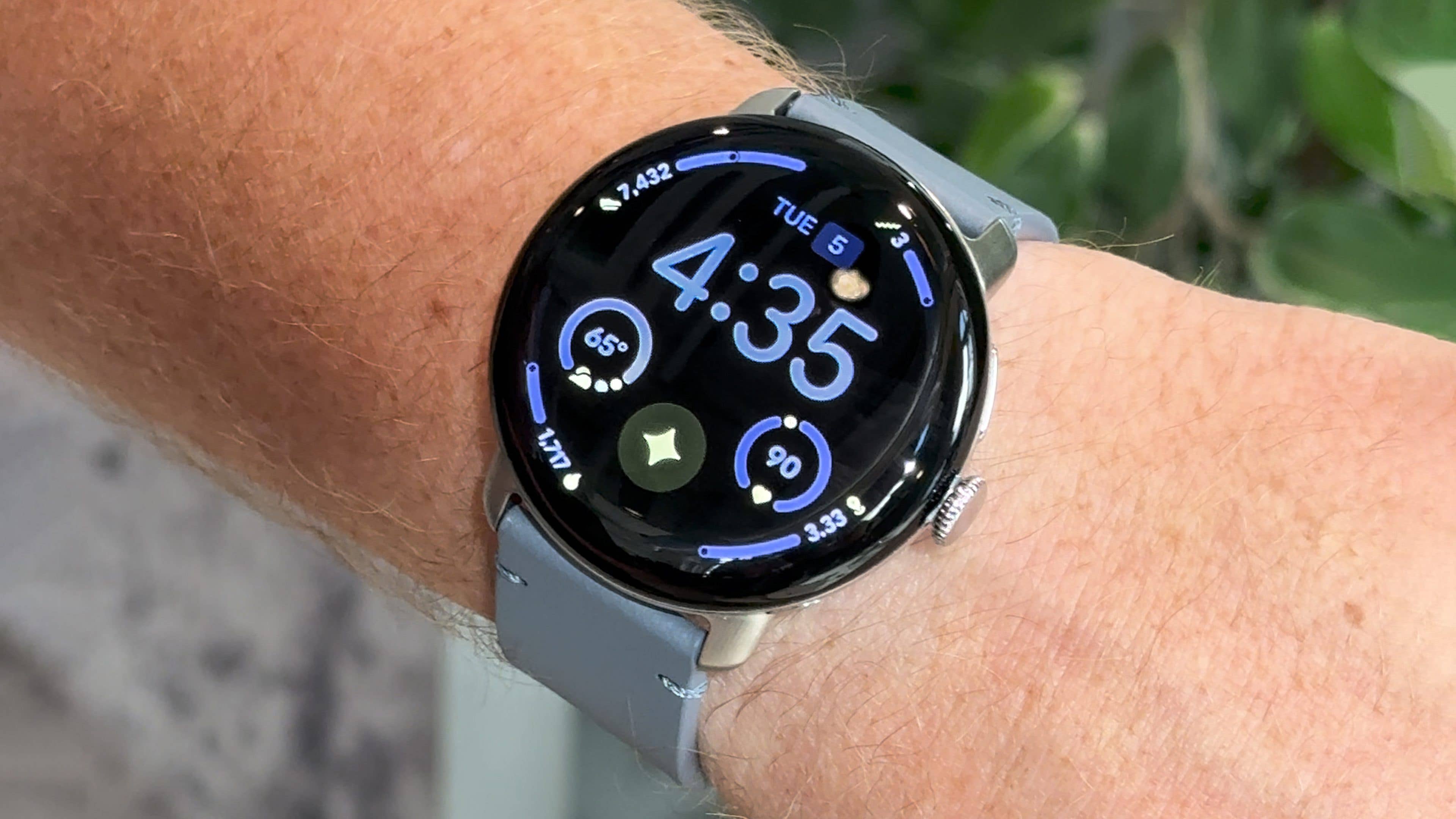 A Google Pixel Watch 4 displaying the time 4:35 and various health metrics on a wrist.