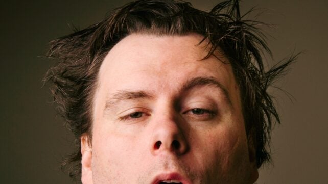 A middle-aged man with messy hair, looking tired