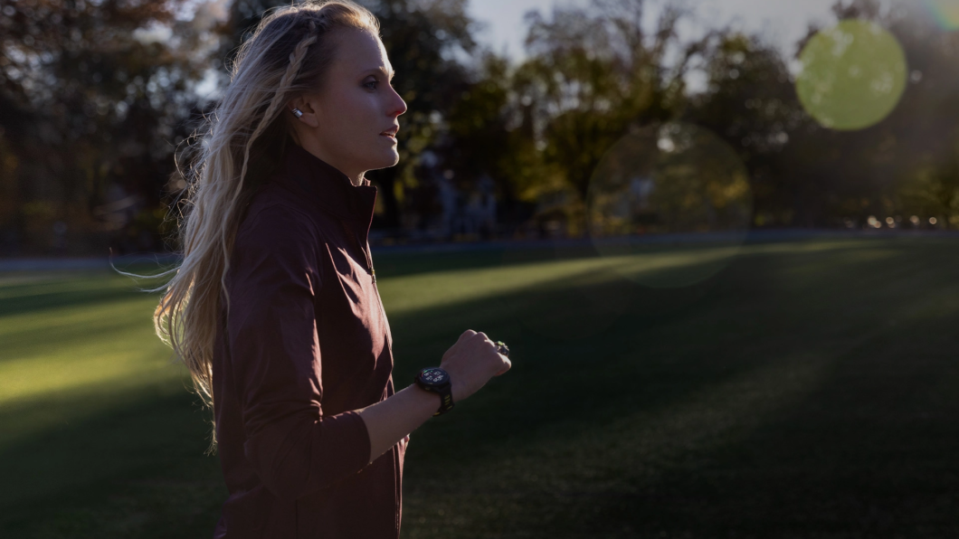 Mulher correndo ao ar livre com o Garmini Forerunner 265 no pulso.
