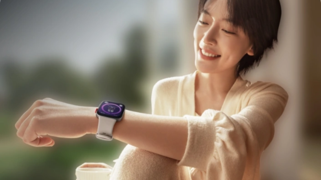 Mulher segurando um copo e olhando a tela do Huawei Watch Fit 3 amarrado no pulso
