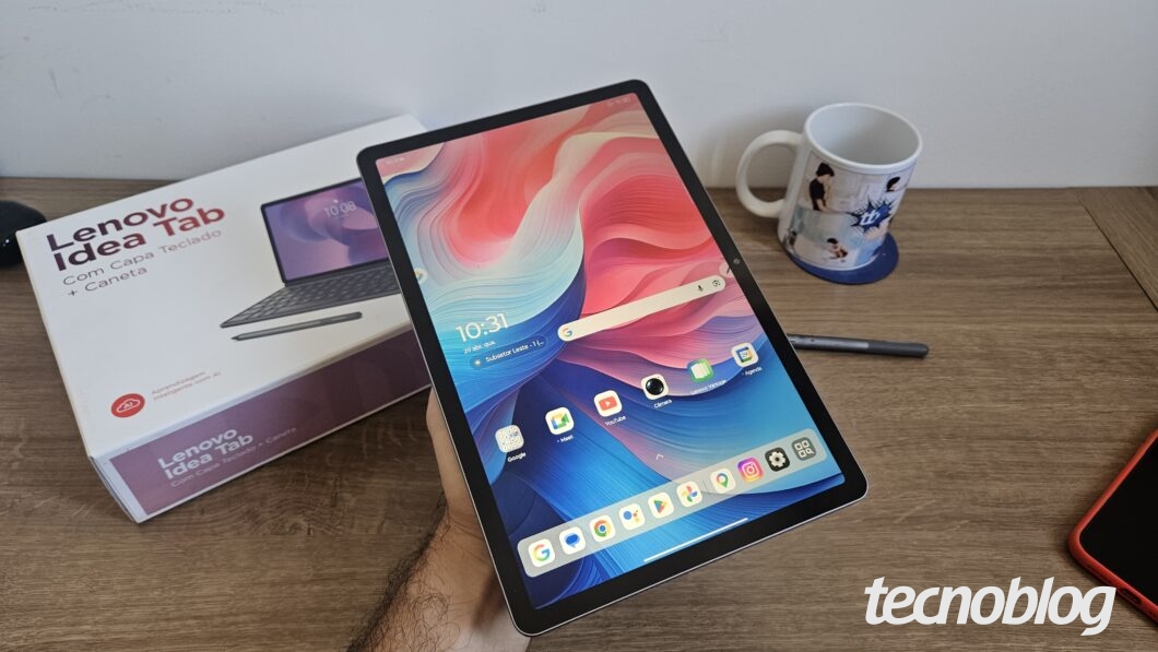 Tela de início do Lenovo Idea Tab; cenário composto pela caixa do produto, caneta do tablet e uma caneca do Tecnoblog.