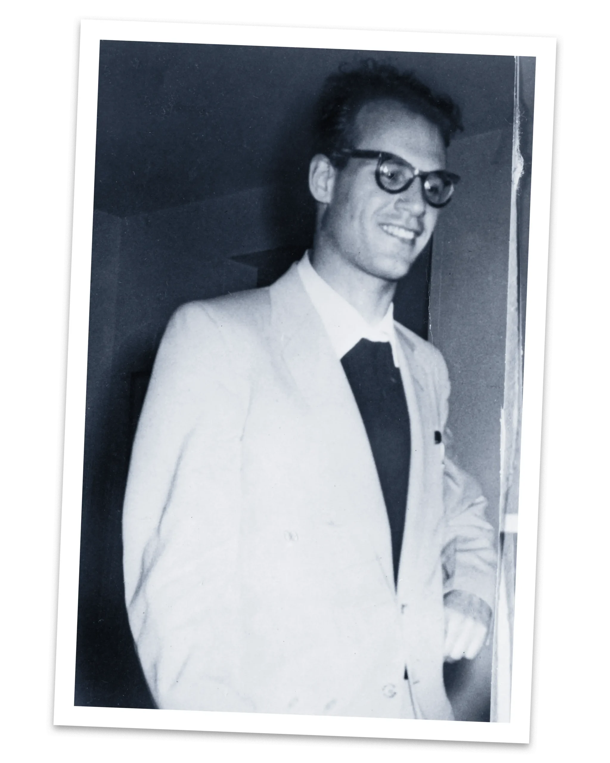 A smiling young man with glasses and a suit