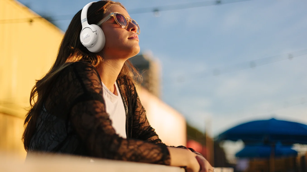 Mulher branca olhando para o céu e usando o JBL Tune 780NC na cor branco