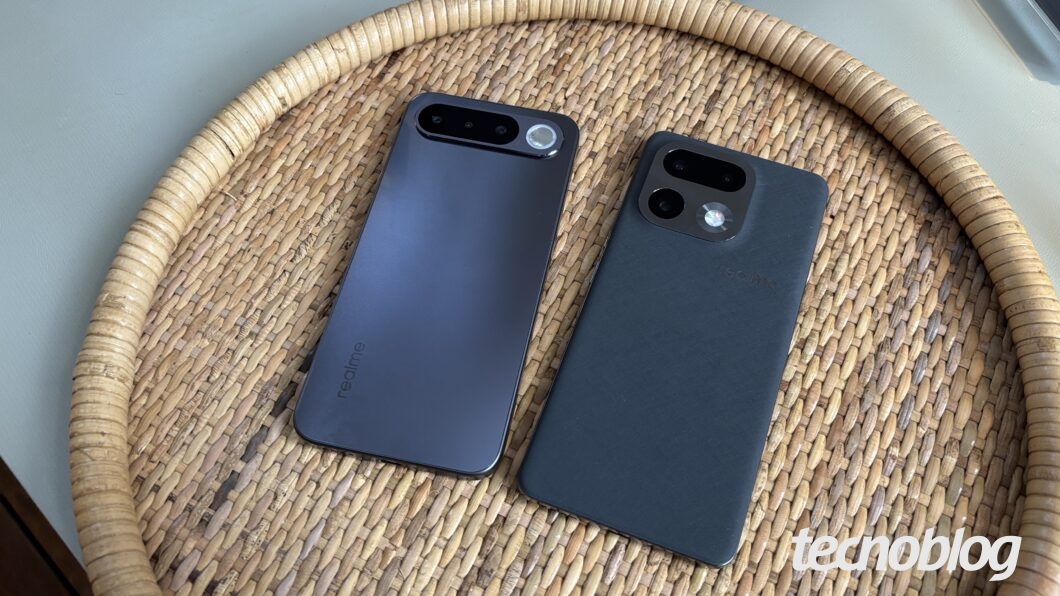 Dois smartphones cinza escuro virados para baixo, em uma bandeja de vime