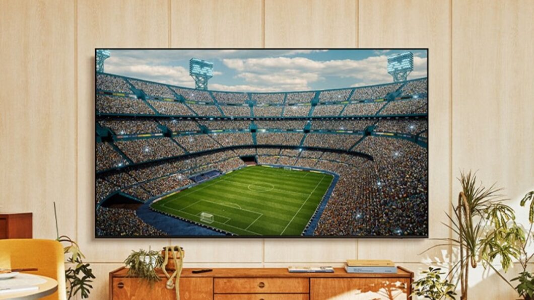 Smart TV Samsung Crystal UHD U8500F exibindo uma partida de futebol em estádio, em ambiente doméstico