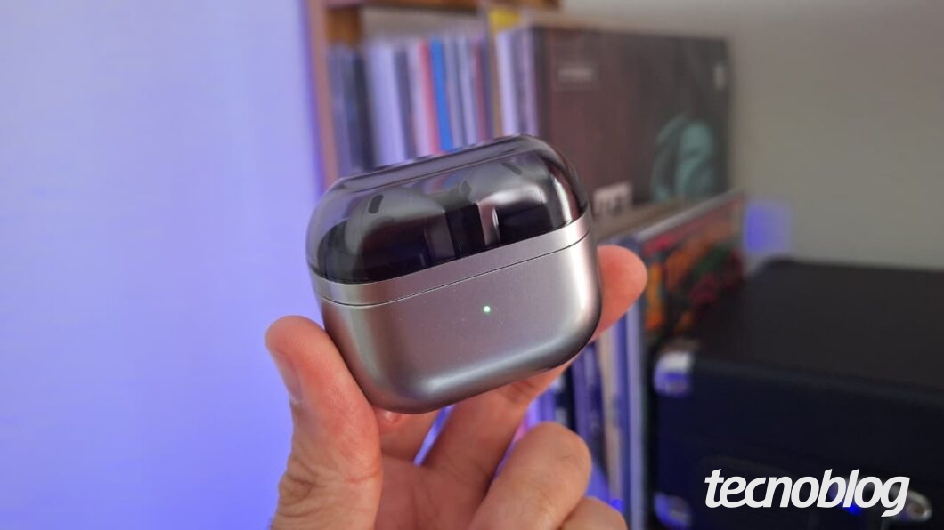 Galaxy Buds 3 em mãos, visto em estúdio com fundo de estantes e iluminação azul