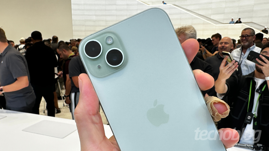 Câmeras traseiras do iPhone 15 em destaque, em evento, com a mão segurando o aparelho