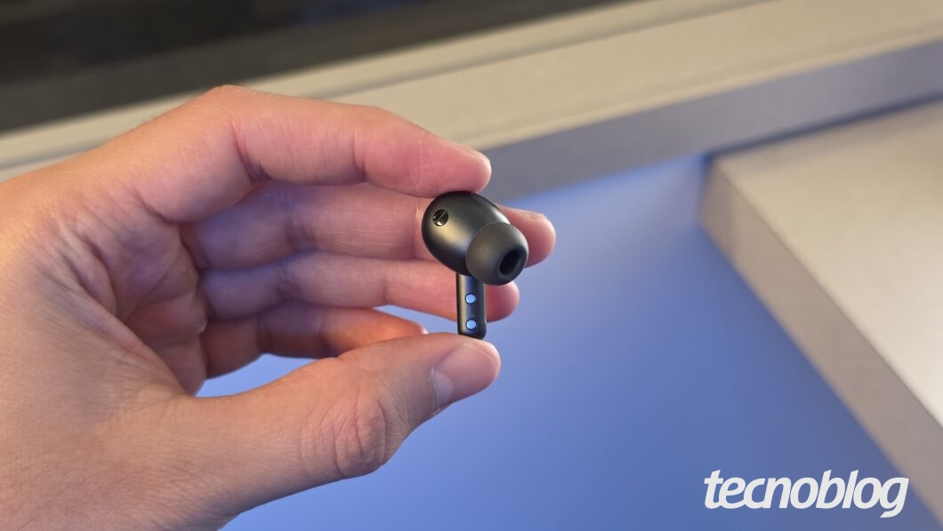 Galaxy Buds 4 Pro da cor preto sendo segurado na mão, com microfone e botões frontais visíveis