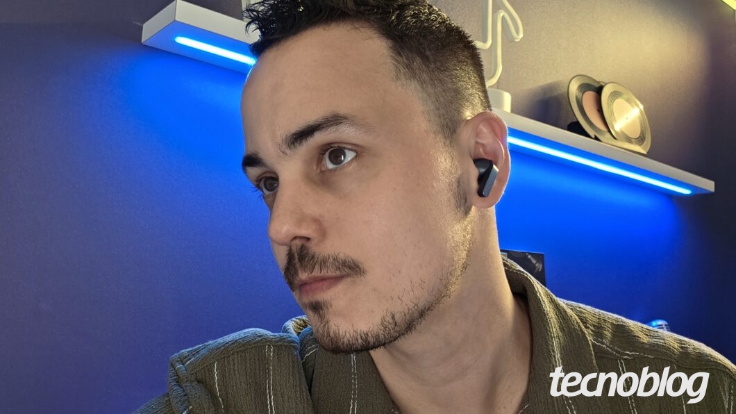 Homem usando o Galaxy Buds 4 Pro em frente a luzes azuis em um ambiente de trabalho