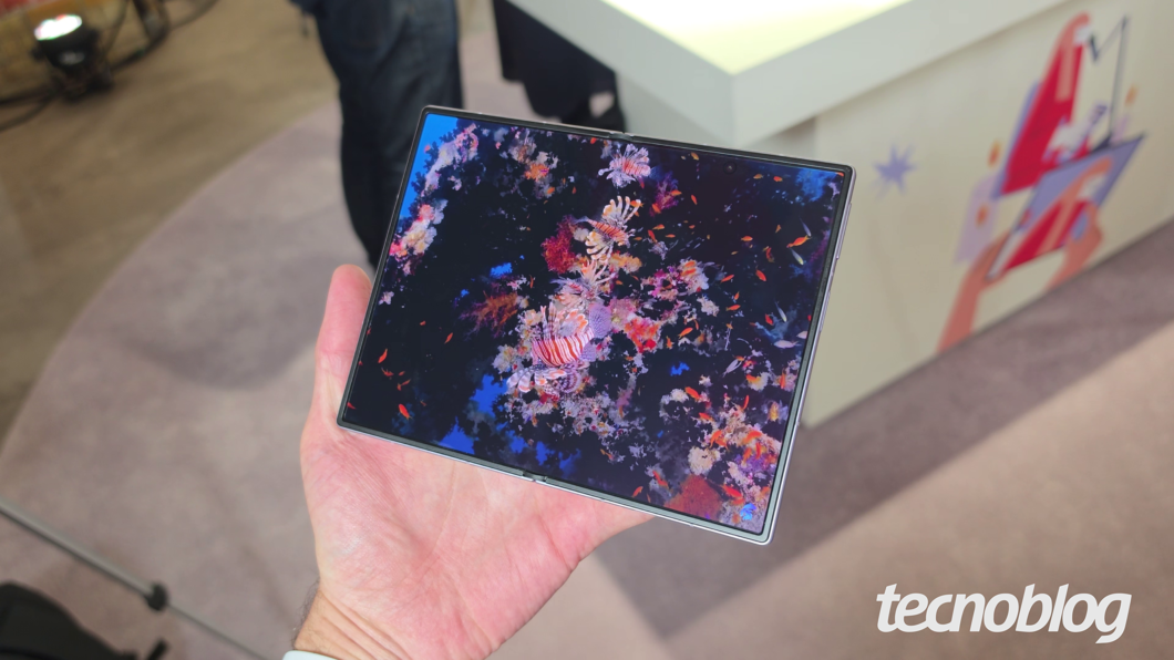 Galaxy Z Fold 8 sendo segurado em uma mão, com todo o painel aberto exibindo uma imagem do fundo do mar, cheia de detalhes