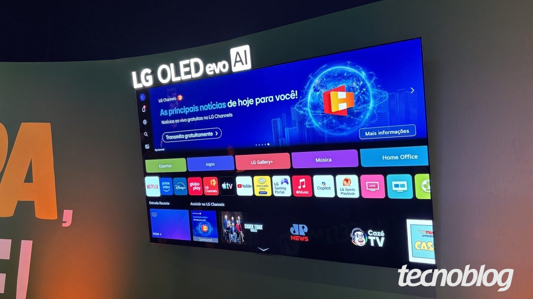 Smart TV da LG fixada em parede cinza em ângulo diagonal. No topo do aparelho, uma placa luminosa exibe o texto "LG OLED evo AI". A tela exibe a interface do sistema webOS com fundo azul, onde se lê "As principais notícias de hoje para você!" e "Transmita gratuitamente". Abaixo do banner, há vários ícones de aplicativos de streaming e utilitários, como Netflix, Prime Video, GloboPlay, YouTube, Mercado Play e Copilot, além de atalhos para categorias coloridas.