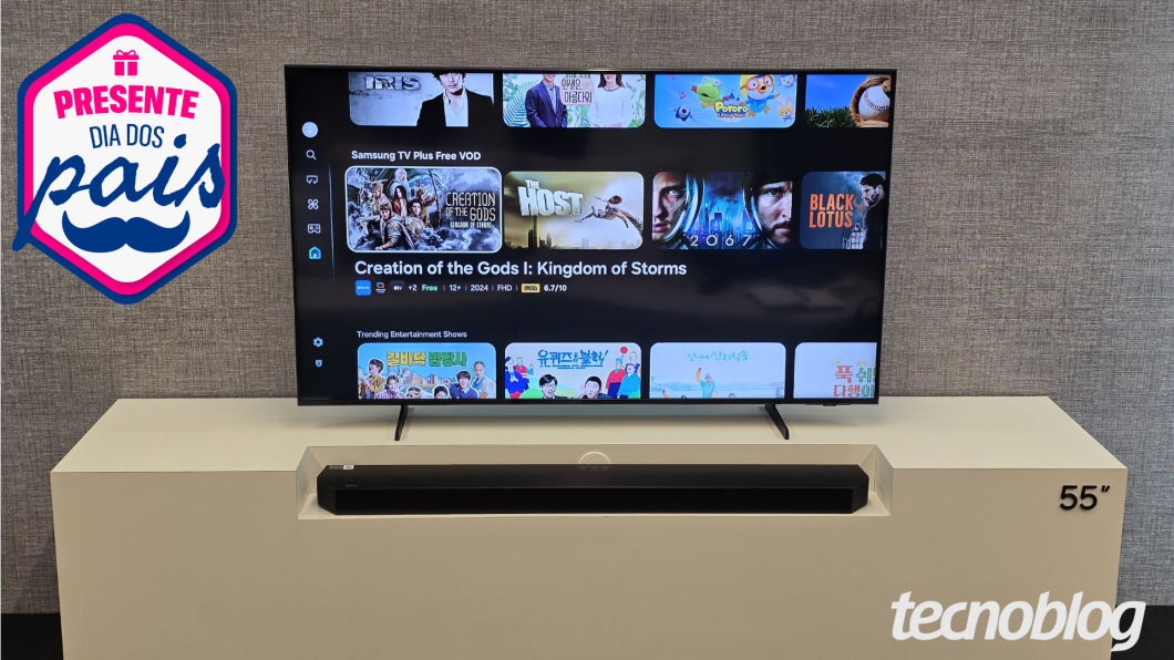 Samsung Q7F ligada mostrando conteúdos da Samsung TV Plus; televisão está sobre um móvel