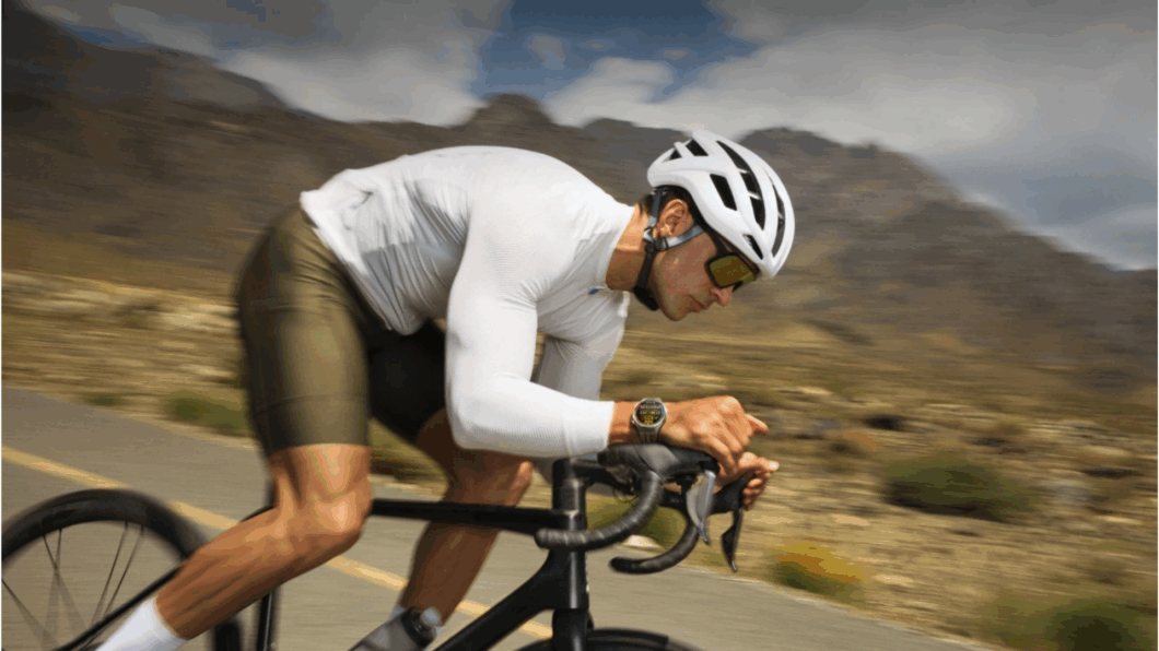 Ciclista pedalando em uma estrada com o Huawei GT 6 Pro no pulso. Ao fundo um cenário rodeado por montanhas desfocadas.